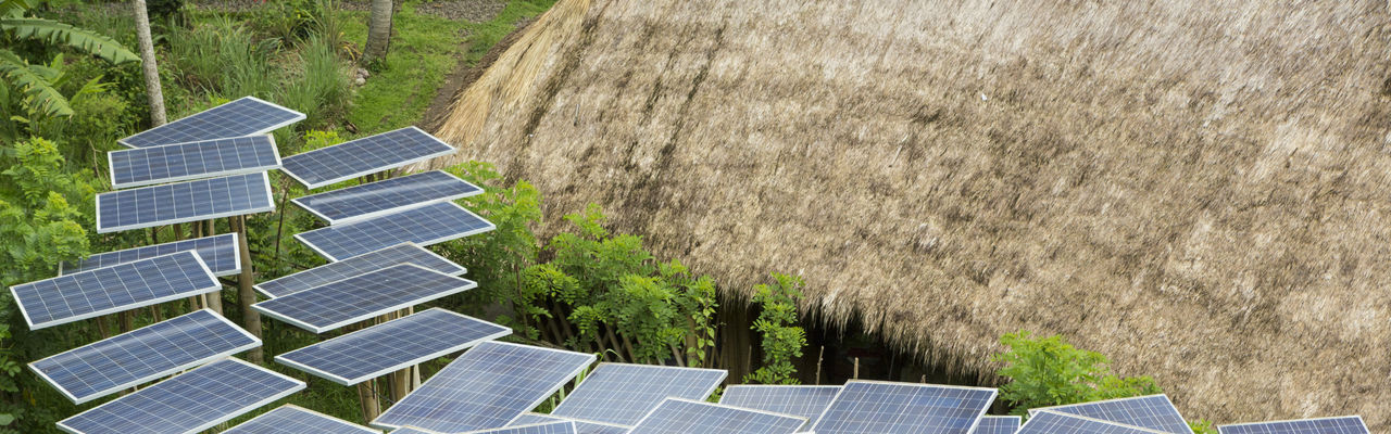 solar panels next to grass roof hut